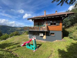 ein Haus auf einem Hügel mit einer Rutsche davor in der Unterkunft Chalet Les Sapins sauna au pied des pistes in La Bresse