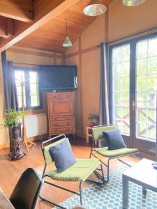 a living room with two chairs and a tv at Le chalet bucolique au bord de l'eau in Olivet