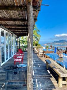 um deque de madeira com uma mesa e cadeiras e o oceano em Lar da Lara em Ilhabela