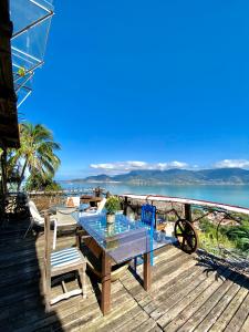 a wooden deck with a table and chairs on the beach at Lar da Lara in Ilhabela