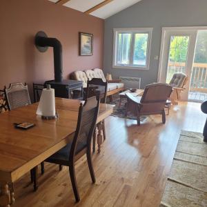 a living room with a table and a wood stove at Le Jasmin chalet complet Rivière Kayak Nature in Saint-Paulin