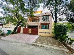 uma casa com um portão vermelho em frente em Holidazzle Lodge Islamabad em Islamabad