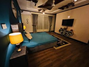 una camera con letto, lampada e televisore di The Comfort Lodge a Islamabad