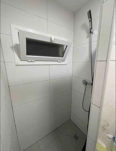 La salle de bains blanche est pourvue d'une douche et d'une fenêtre. dans l'établissement Cozy room next to el prat airport, à El Prat de Llobregat
