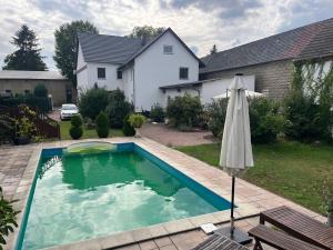 a swimming pool with an umbrella and a house at Wormis Apartment Heideblick bei Luckau in Heideblick