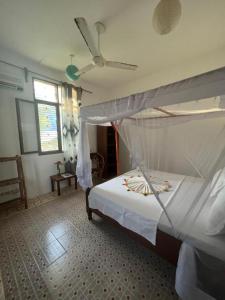 a bedroom with a bed and a ceiling fan at Mauwa House in Paje