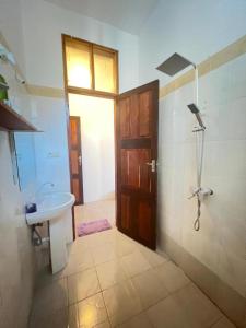 baño con lavabo, ducha y puerta en Mauwa House en Paje