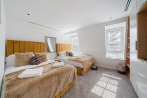 a bedroom with two beds and two windows at Marble Arch Penthouse 3 Bed in London