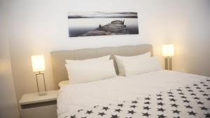 ein Schlafzimmer mit einem großen weißen Bett mit zwei Lampen in der Unterkunft Riff I in Norddeich