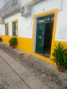 ein gelbes und weißes Gebäude mit grüner Tür in der Unterkunft VISIT MOURA - Solar das Flores in Moura