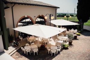 einen Blick über eine Terrasse mit Tischen und weißen Sonnenschirmen in der Unterkunft Albergo La Meridiana in Castelnuovo del Garda