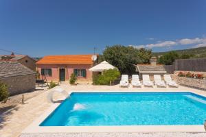 a swimming pool with chairs and a house at Stone houses Nikola in Podorljak