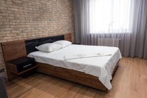 Cette chambre comprend un lit avec des draps blancs et un mur en briques. dans l'établissement Байди Вишневецького 68, à Tcherkassy