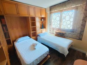 twee bedden in een kleine kamer met een raam bij La Elegancia del Centro by Alogest in Zaragoza
