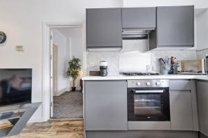 cocina con armarios blancos y horno en Cosy Coastal Haven 1-Bedroom Apartment in Southend-On-Sea - Southend Stays, en Southend-on-Sea