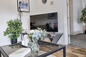 a living room with a glass table with a vase of flowers at Cosy Coastal Haven 1-Bedroom Apartment in Southend-On-Sea - Southend Stays in Southend-on-Sea
