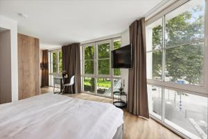 a bedroom with a large bed and large windows at Home and CoLiving Bonn I Aparthotel I Soft Opening in Bonn