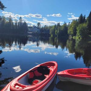 Deux bateaux rouges sont assis sur un lac dans l'établissement Le Jasmin chalet complet Rivière Kayak Nature, à Saint-Paulin
