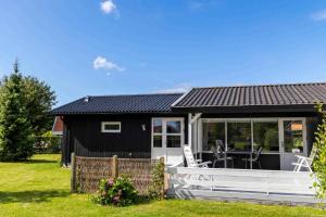 Ce cottage noir et blanc dispose d'une terrasse couverte. dans l'établissement Liljeparken 30, à Otterup