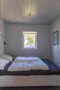 Cama en habitación blanca con ventana en Liljeparken 30, en Otterup