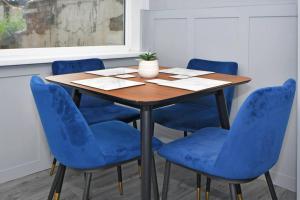 une table avec des chaises bleues dans une pièce dans l'établissement Barnstone Villa - By Sigma Stays, à Crewe