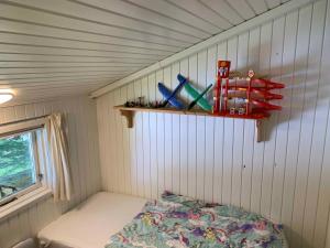 ein kleines Zimmer mit einem Bett und einem Regal an der Wand in der Unterkunft Cosy Summer House Close To Beach, Woods And Town in Fjerritslev