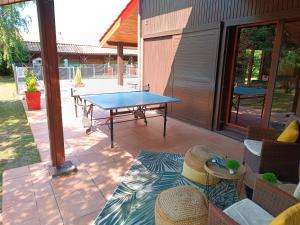 une terrasse avec une table de ping-pong et des chaises dans l'établissement MagHouse, à Cestas