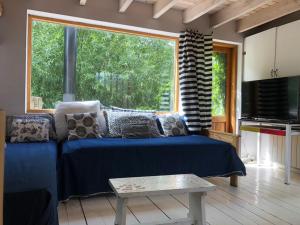 a living room with a blue couch and a large window at Casa Las Moras in San Martín de los Andes