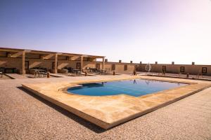 a large swimming pool in the middle of a courtyard at Traditional Riad Merzouga Dunes in Merzouga