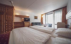 a hotel room with two beds and a television at Club Hotel rooms only - by Mountain Hotels in Davos +12 photos