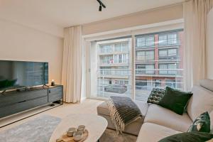 a living room with a couch and a large window at Sun & sea Knokke in Knokke-Heist