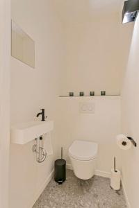 a white bathroom with a toilet and a sink at Sun & sea Knokke in Knokke-Heist