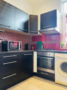 a kitchen with black cabinets and a microwave and a washing machine at Downtown Quiet and Peacefull Apartment in Brussels