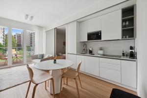 uma cozinha com armários brancos e uma mesa e cadeiras em limehome Milan via Stresa em Milão