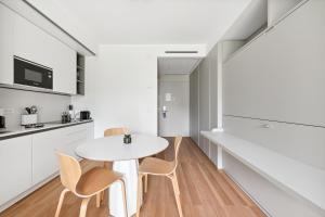 a white kitchen with a white table and chairs at Limehome Milan via Stresa in Milan +28 photos