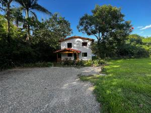 a small white house with a gravel driveway at Villa unter Palmen in Jarabacoa