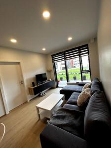 ein Wohnzimmer mit einem schwarzen Sofa und einem Tisch in der Unterkunft A modern & homely apartment in Reykjavík