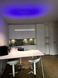 a kitchen with white cabinets and a purple ceiling at A modern & homely apartment in Reykjavík