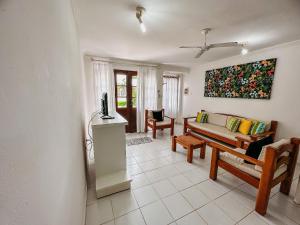 uma sala de estar com um sofá e uma pintura na parede em A 200m da praia de Taperapuã, (Axé Mói) 2 suítes piscina, sauna, portaria 24hrs internet privativa 300MBPS em Porto Seguro