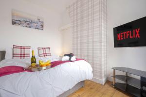 a bed with a tray of fruit and a bottle of wine at 3 Bedroom House in City Centre - Sleeps up to 7 - Free Parking, Fast Wifi, Pool Table and SmartTV with SkyTV and Netflix by Yoko Property in Northampton