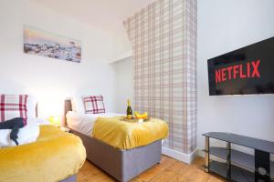 een slaapkamer met 2 bedden en een netflix-bord aan de muur bij 3 Bedroom House in City Centre - Sleeps up to 7 - Free Parking, Fast Wifi, Pool Table and SmartTV with SkyTV and Netflix by Yoko Property in Northampton