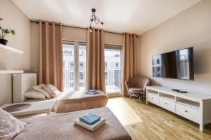 a bedroom with two beds and a tv at Gama Home Szwedzka 30 in Warsaw