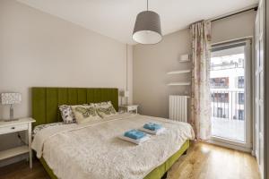1 dormitorio con 1 cama con cabecero verde y ventana en Gama Home Szwedzka 30, en Varsovia