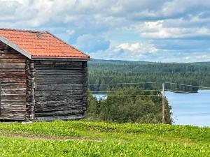 un antiguo edificio de madera sentado en una colina junto a un lago en Holiday home TORPSHAMMAR, en Torpshammar