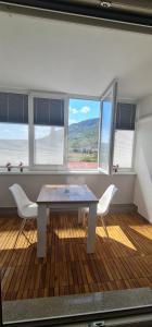a table and chairs in a room with windows at Luxury apartment Sunny place in Mostar