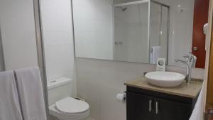 a white bathroom with a toilet and a sink at Hotel Sicarare in Valledupar