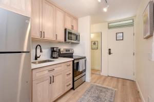 a kitchen with wooden cabinets and a white refrigerator at Kihei Bay Surf 140 in Kihei