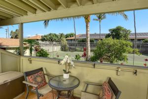 einen Balkon mit einem Tisch, Stühlen und Palmen in der Unterkunft Kihei Bay Surf 140 in Kihei