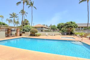 a swimming pool in a resort with palm trees at Kihei Bay Surf 140 in Kihei