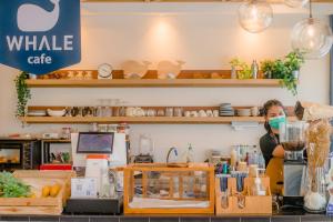 a woman wearing a mask behind a counter in a store at Sleep Whale Hotel in Krabi